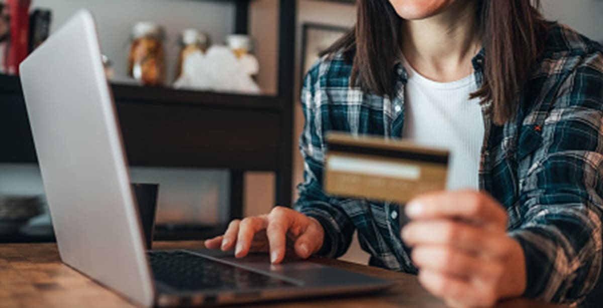 Woman at her computer, holding a credit card