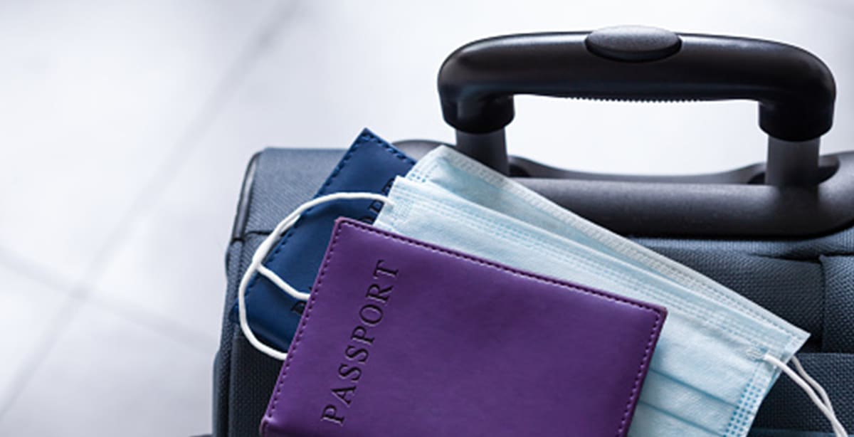 Passport and face masks stacked on a suitcase