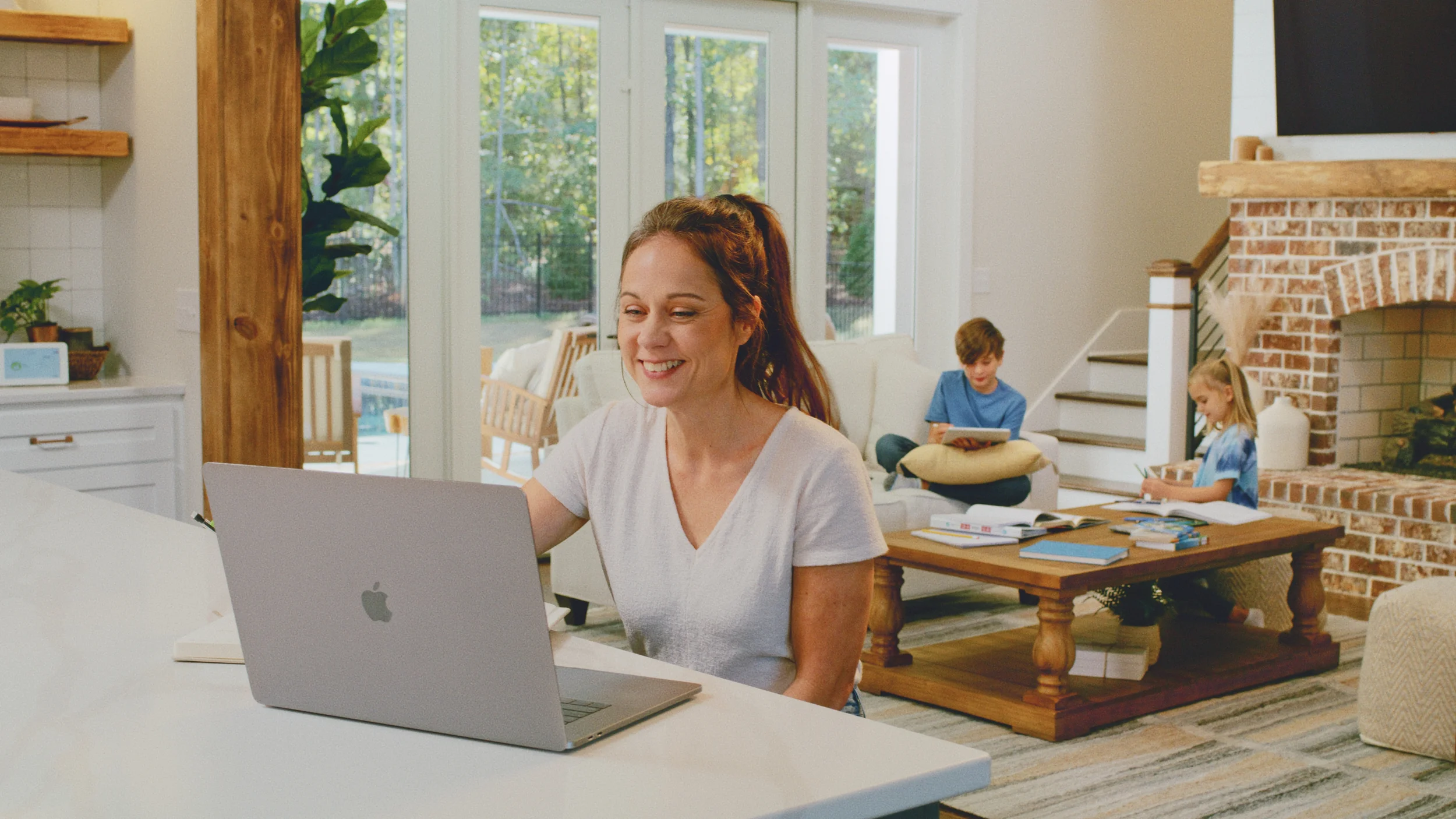 lady sitting at laptop with kids in background