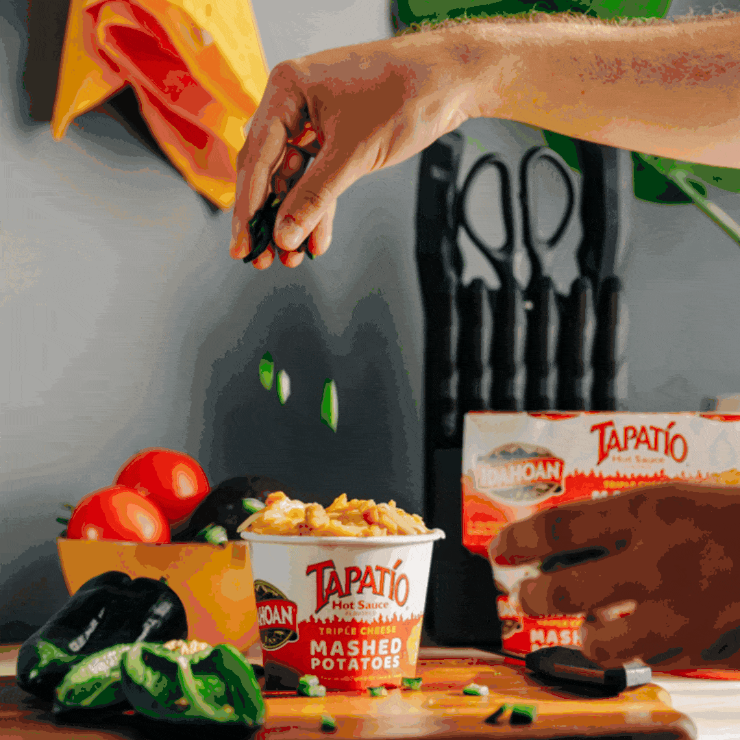 sprinkling peppers on tapatio mashed potato cup