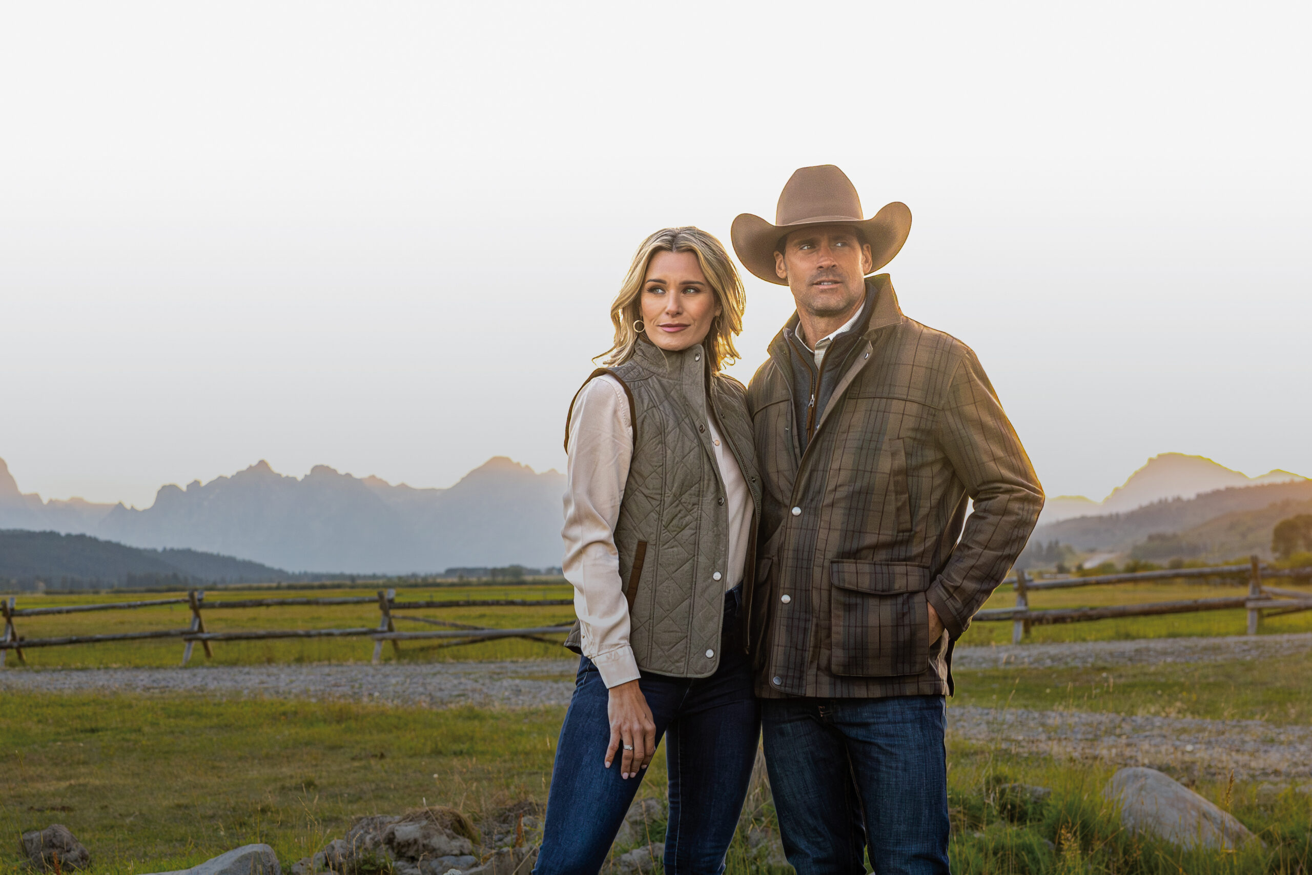 Couple wearing western gear with scenic mountains behind them