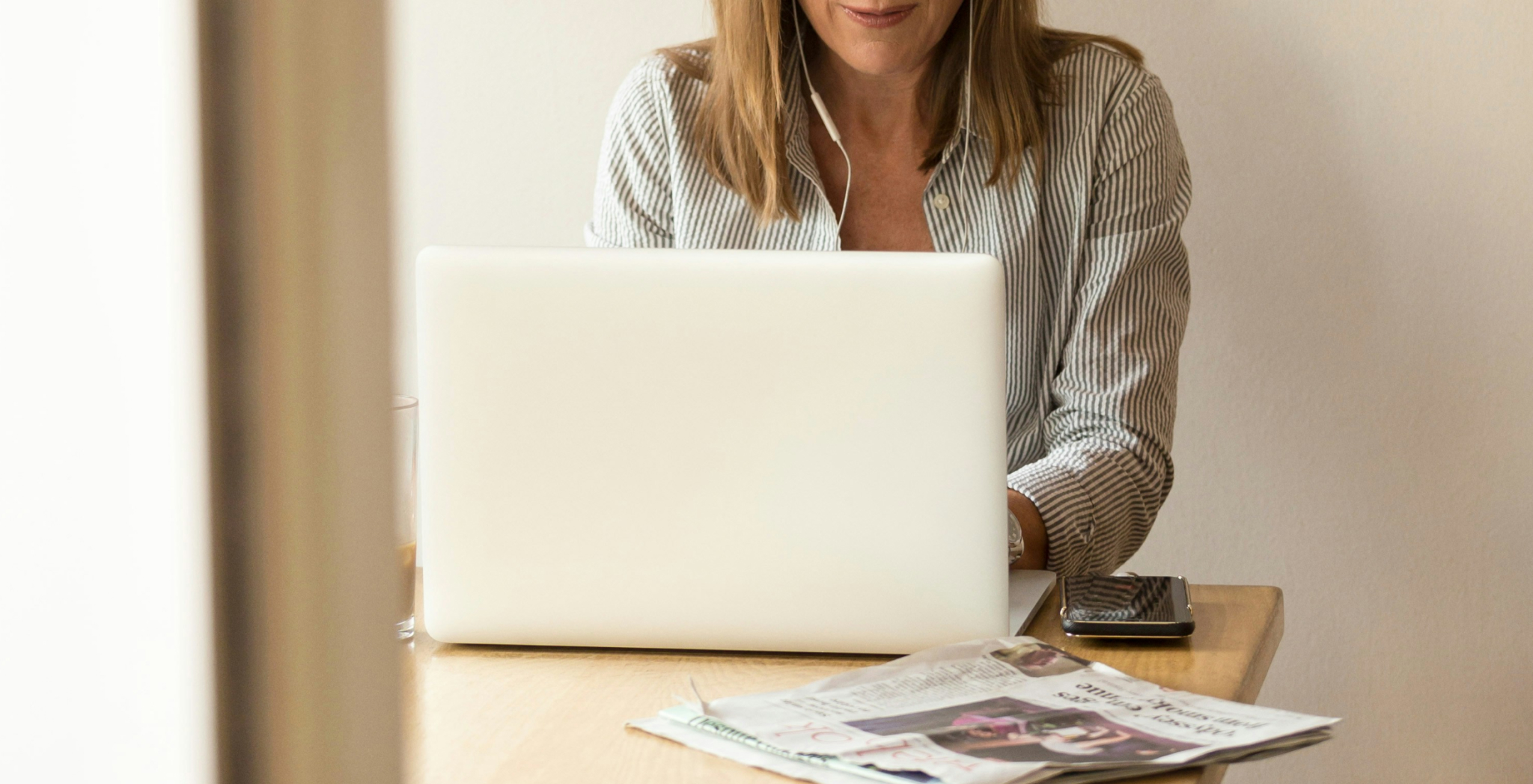 woman at laptop with newspaper